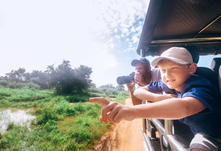 Son and father view animals on safari