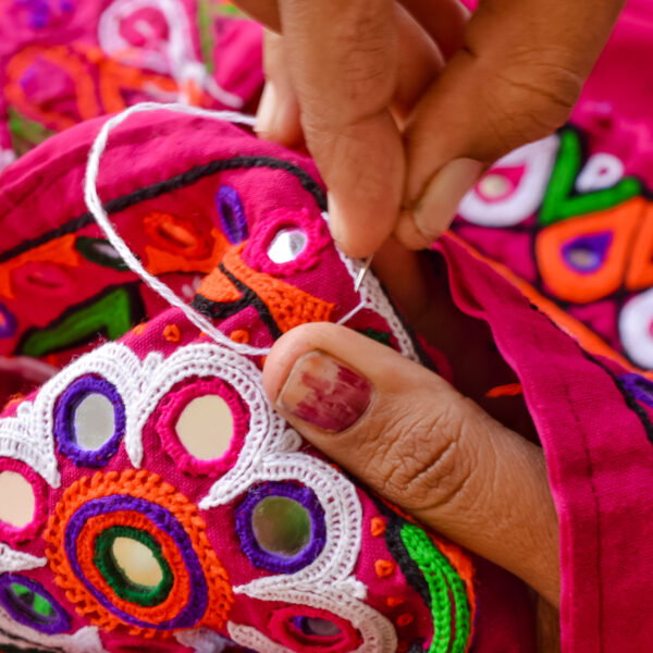 female needlework on fabric material close up view,Unidentified Tribal women sewing ethnic dresses,ahir embroidery art work close up view,Gujarat india embroidery
