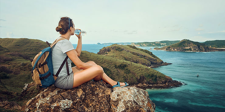 A traveller drinking from a plastic water bottle